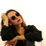 Portrait of a woman in sunglasses and black outfit with a confident pose.